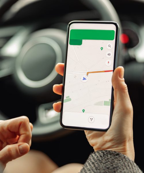 Female driver using cell phone with gps navigation app on screen sitting in car. High quality photo